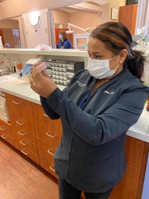 dental team member of Firouzian Dentistry inspecting new dental implant restorations